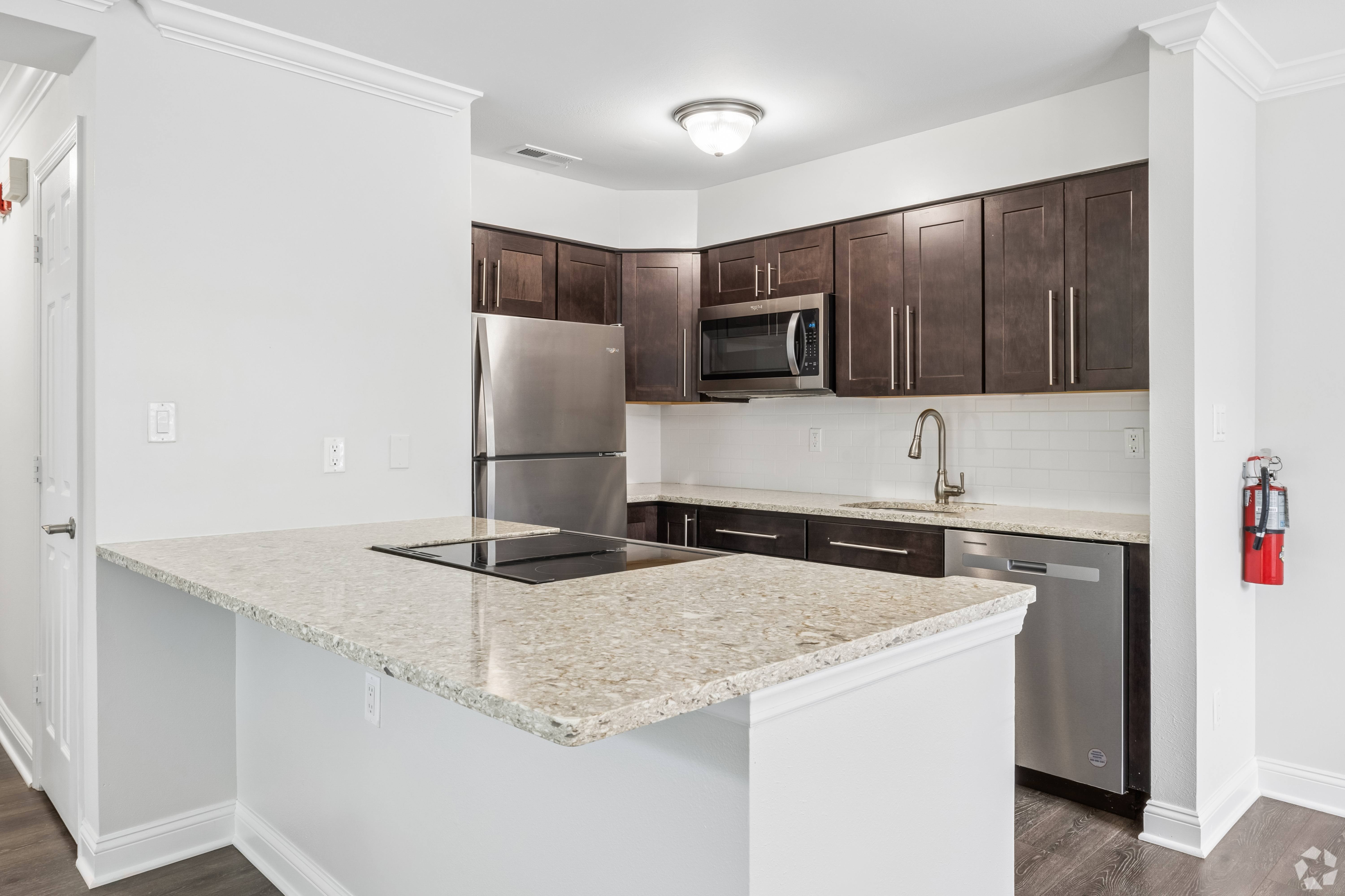 A kitchen with a granite countertop and stainless steel appliances.